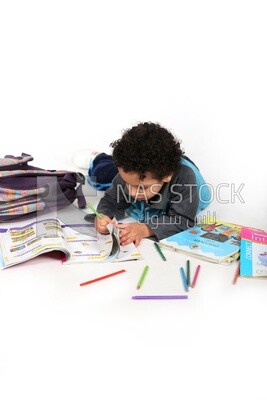 A schoolboy sitting on the floor studying