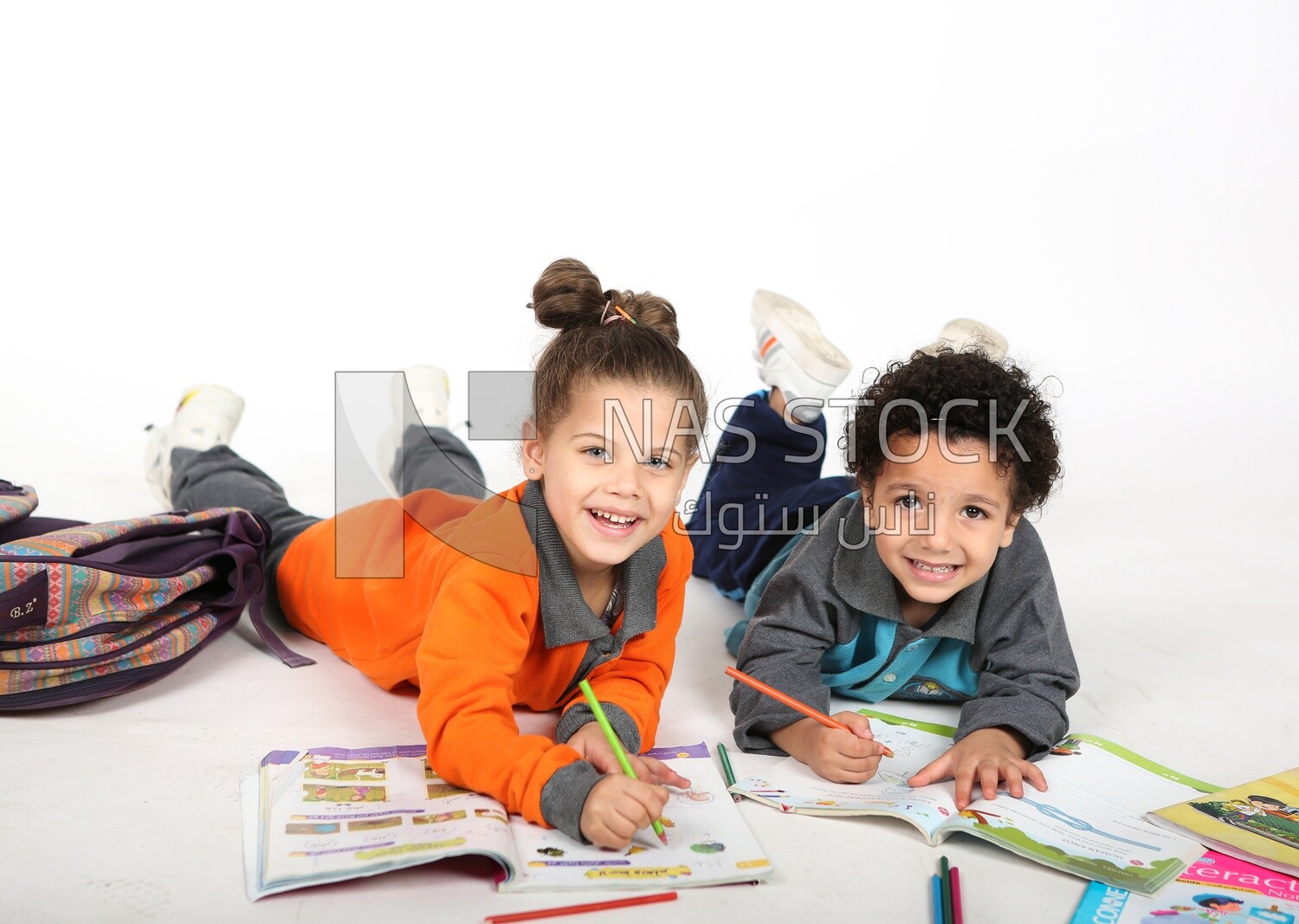 A brother and a sister sitting on the floor studying