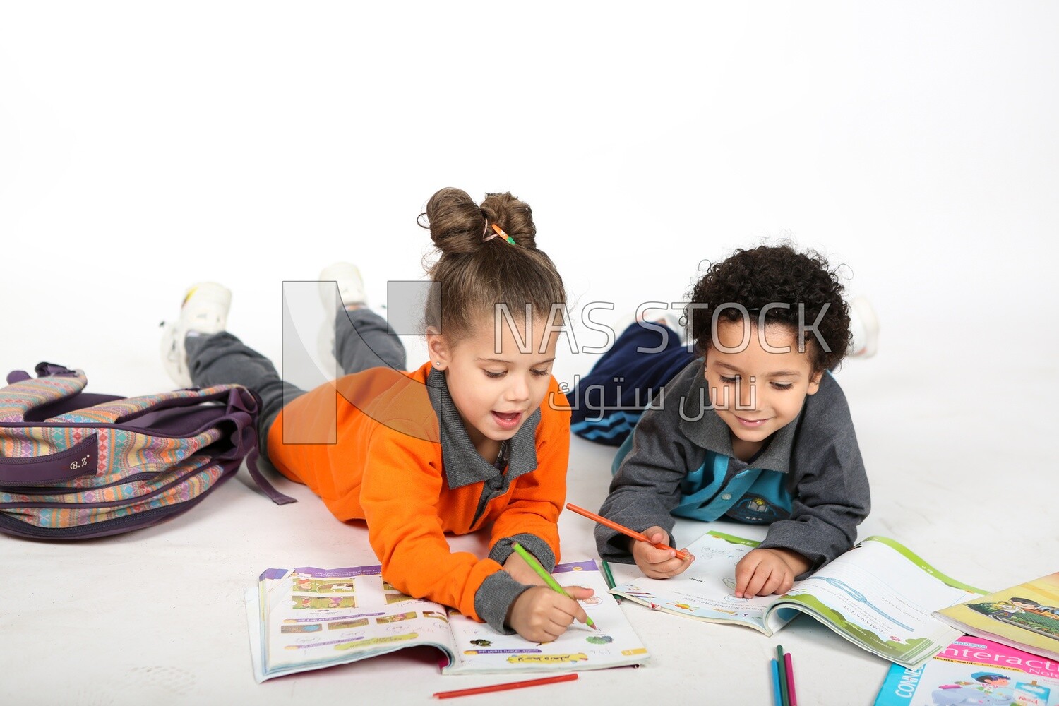 A brother and a sister sitting on the floor studying