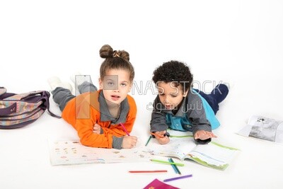 A brother and a sister sitting on the floor studying