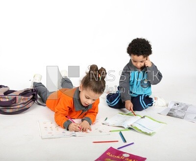 A brother and a sister sitting on the floor studying