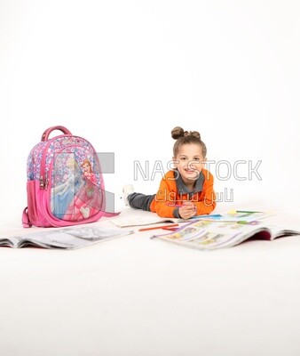 A schoolgirl sitting on the floor and studying