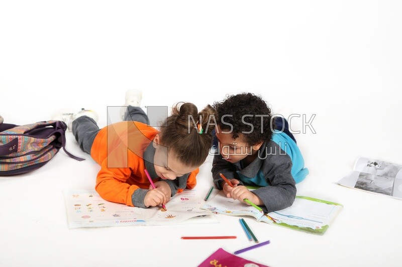 A brother and a sister sitting on the floor studying