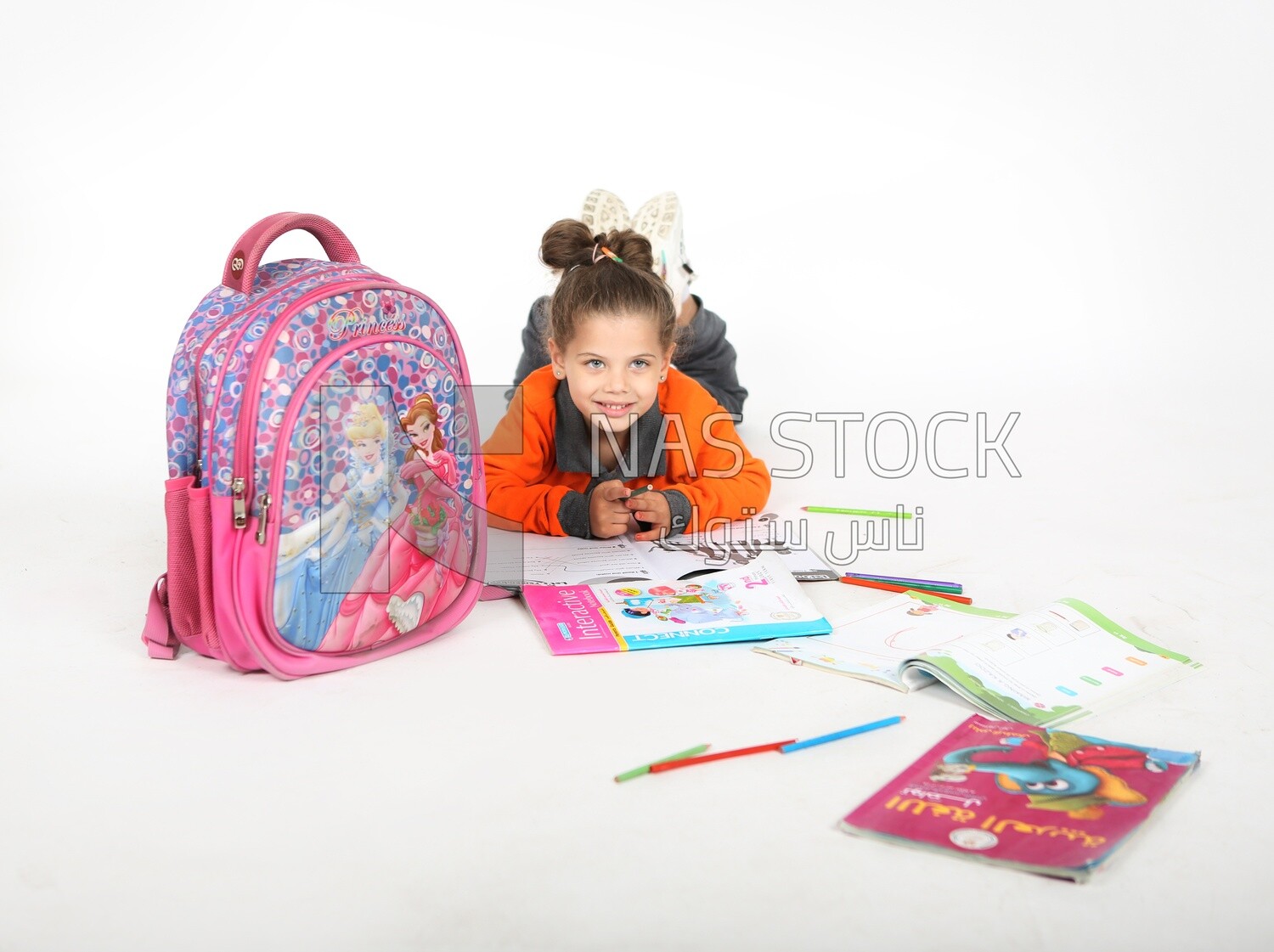 A schoolgirl sitting on the floor and studying