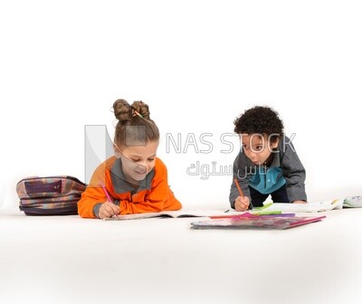 A brother and a sister sitting on the floor studying