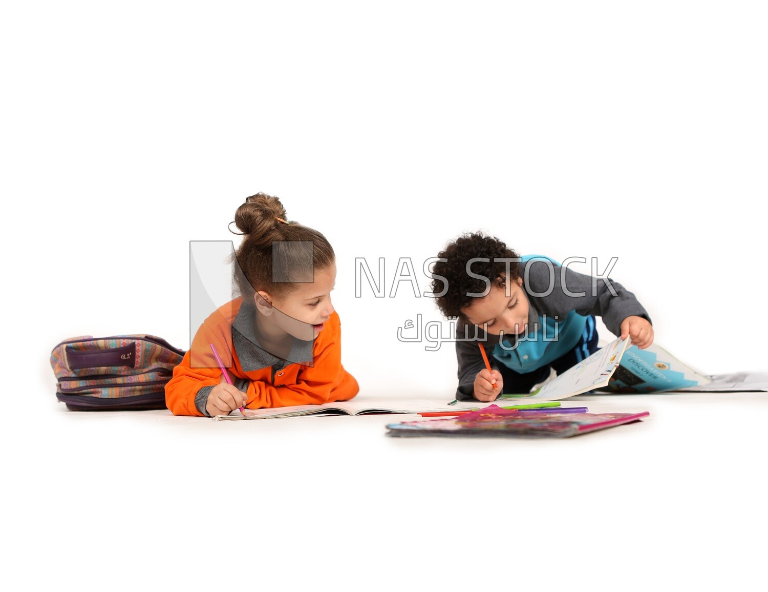 A brother and a sister sitting on the floor studying