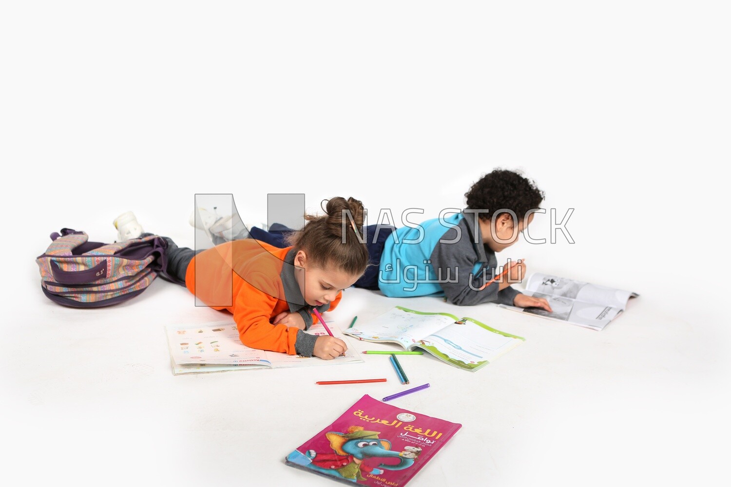 A brother and a sister sitting on the floor studying