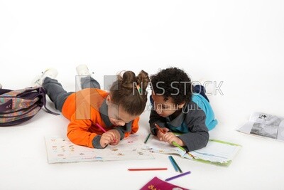 A brother and a sister sitting on the floor studying