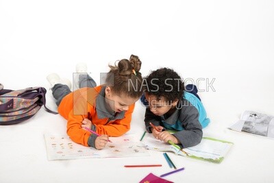 A brother and a sister sitting on the floor studying
