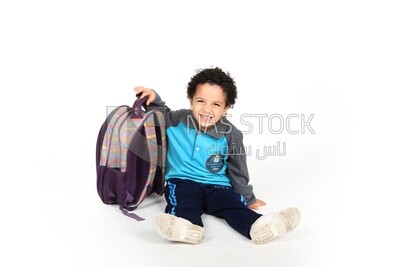 A schoolboy sitting on the floor beside his bag