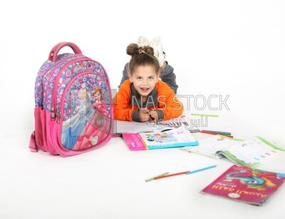 A schoolgirl sitting on the floor and studying