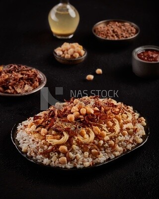 منظر جانبى لطاولة طعام بها طبق كشرى مصرى مع اطباق للعدس و البصل المقلى