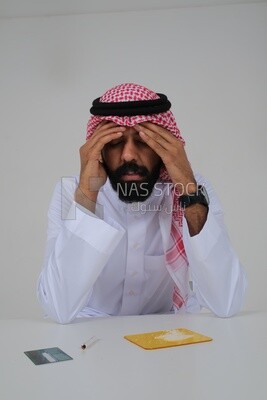Saudi man sitting in front of many types of toxic substances, tobacco addiction, cigarette addiction, harmful and toxic substance abuse, harmful behavioral habits, no smoking, Saudi model