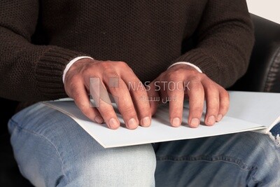 blind man reading a book in Braille