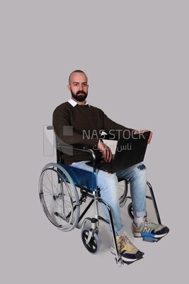 Disabled man in a wheelchair working on a laptop