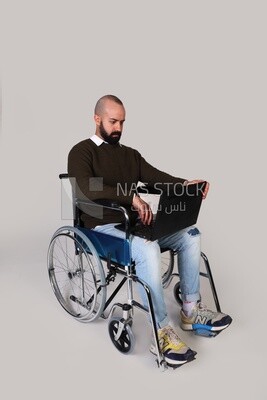 Disabled man in a wheelchair working on a laptop