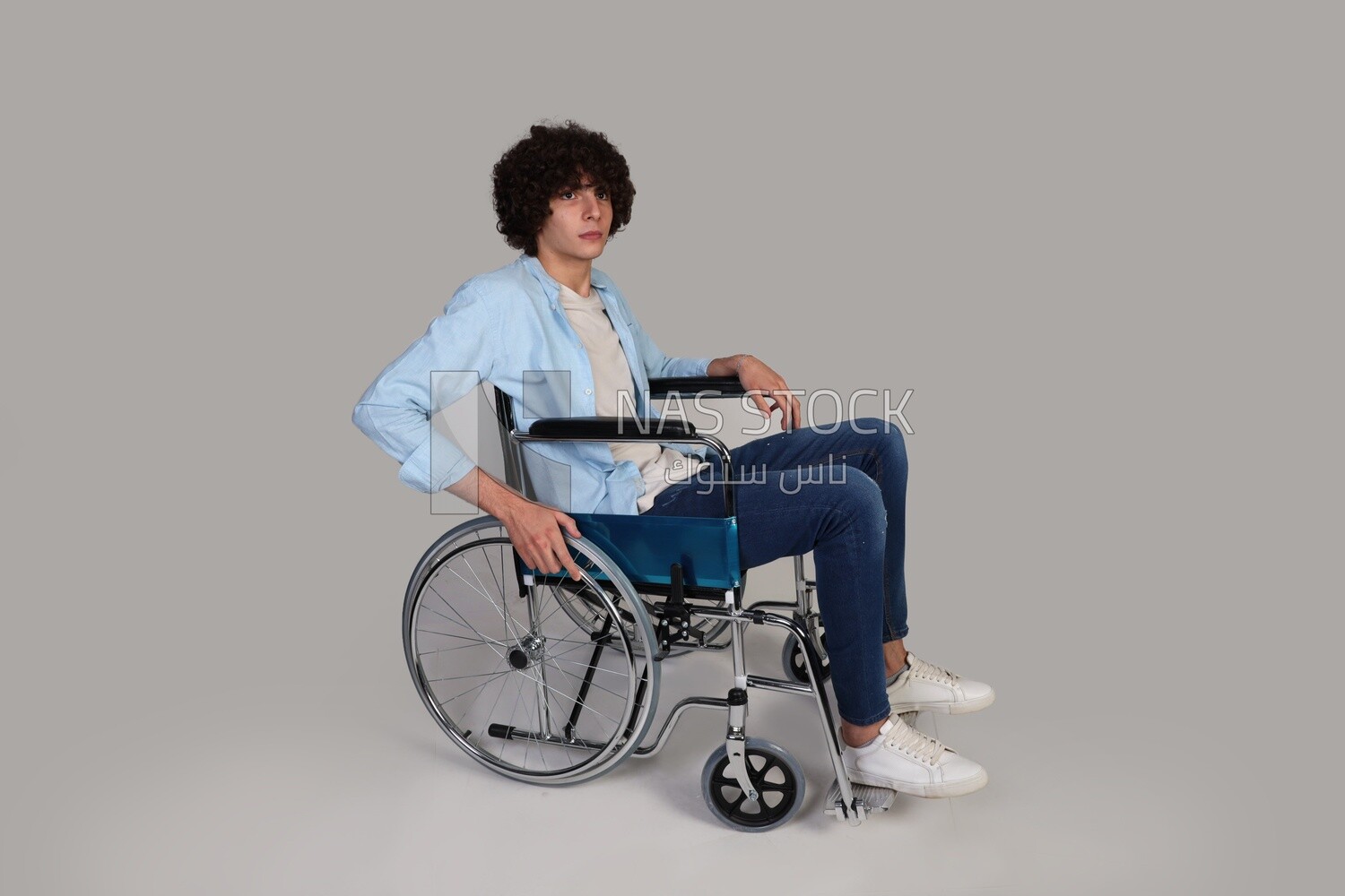 disabled young man with thick curly hair sitting in a wheelchair
