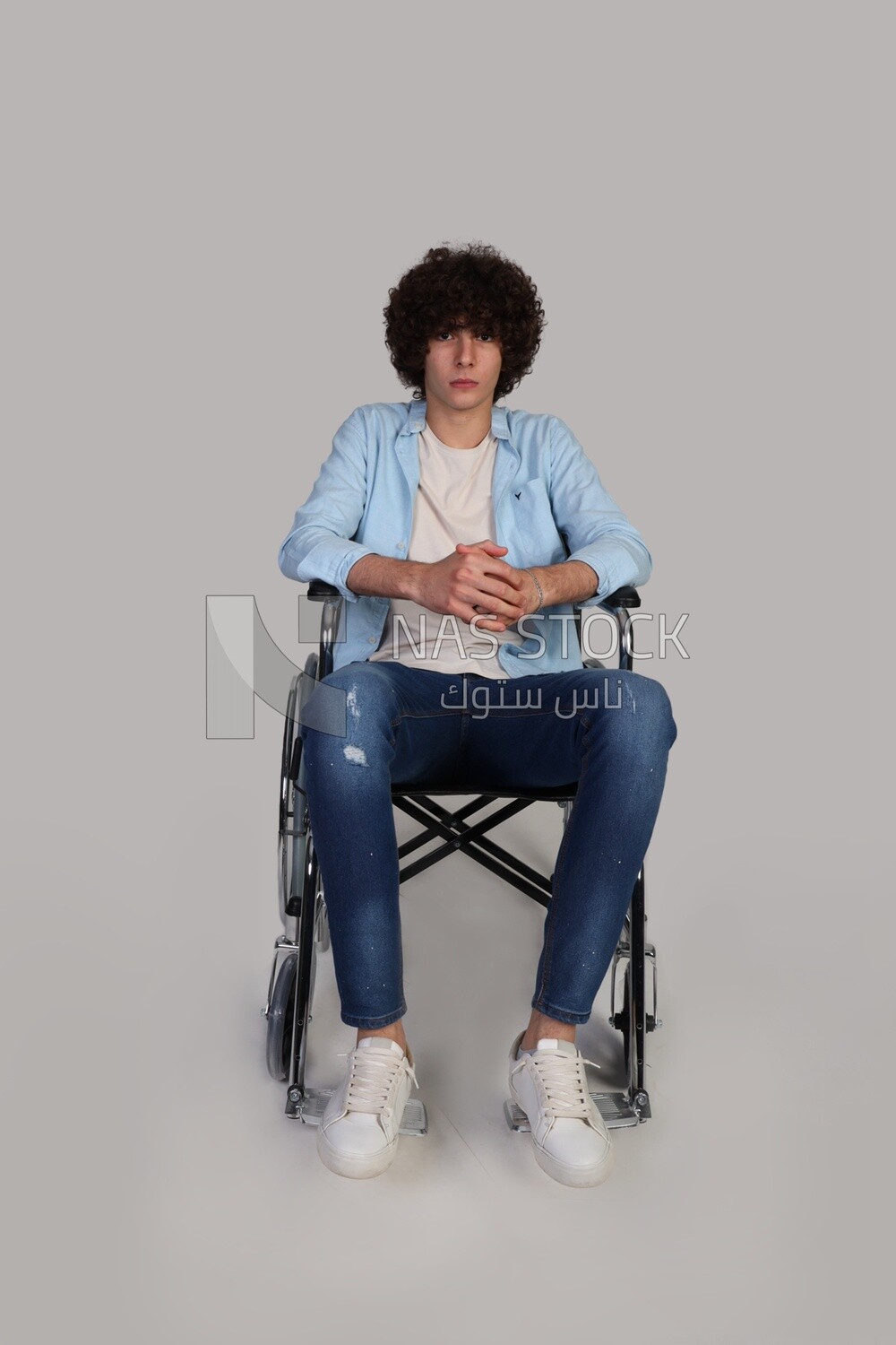 disabled young man with thick curly hair sitting in a wheelchair