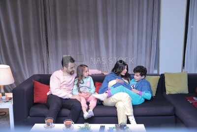 a family of four sitting on the sofa talking together