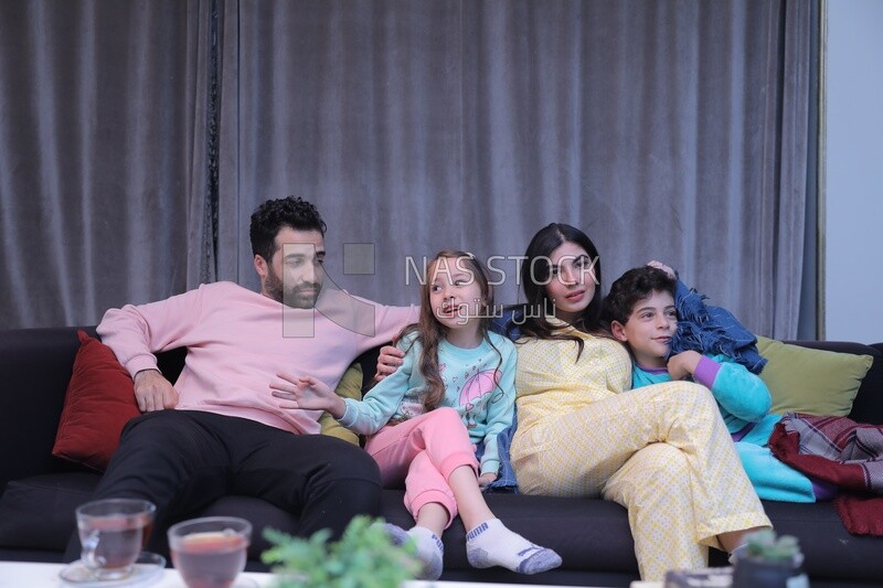 a family of four sitting on the sofa talking together