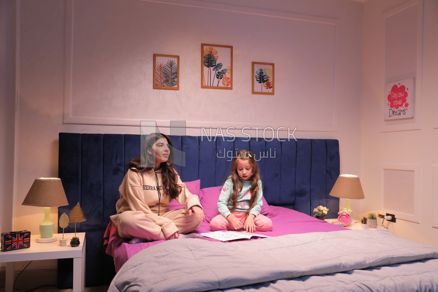 a mother sitting with her daughter and talking in the bed