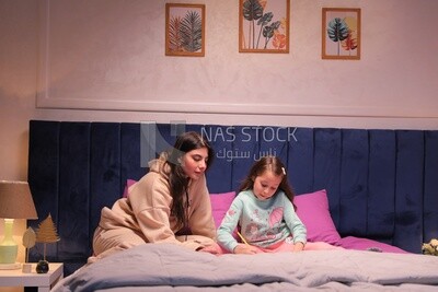 a mother with her daughter drawing together on the bed