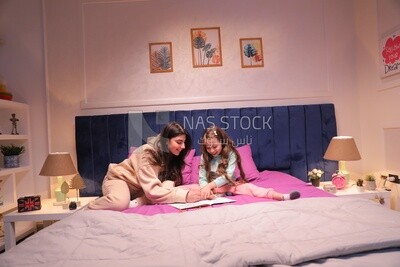a mother with her daughter drawing together on the bed