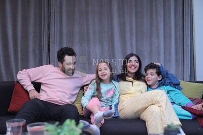 a family of four sitting on the sofa laughing