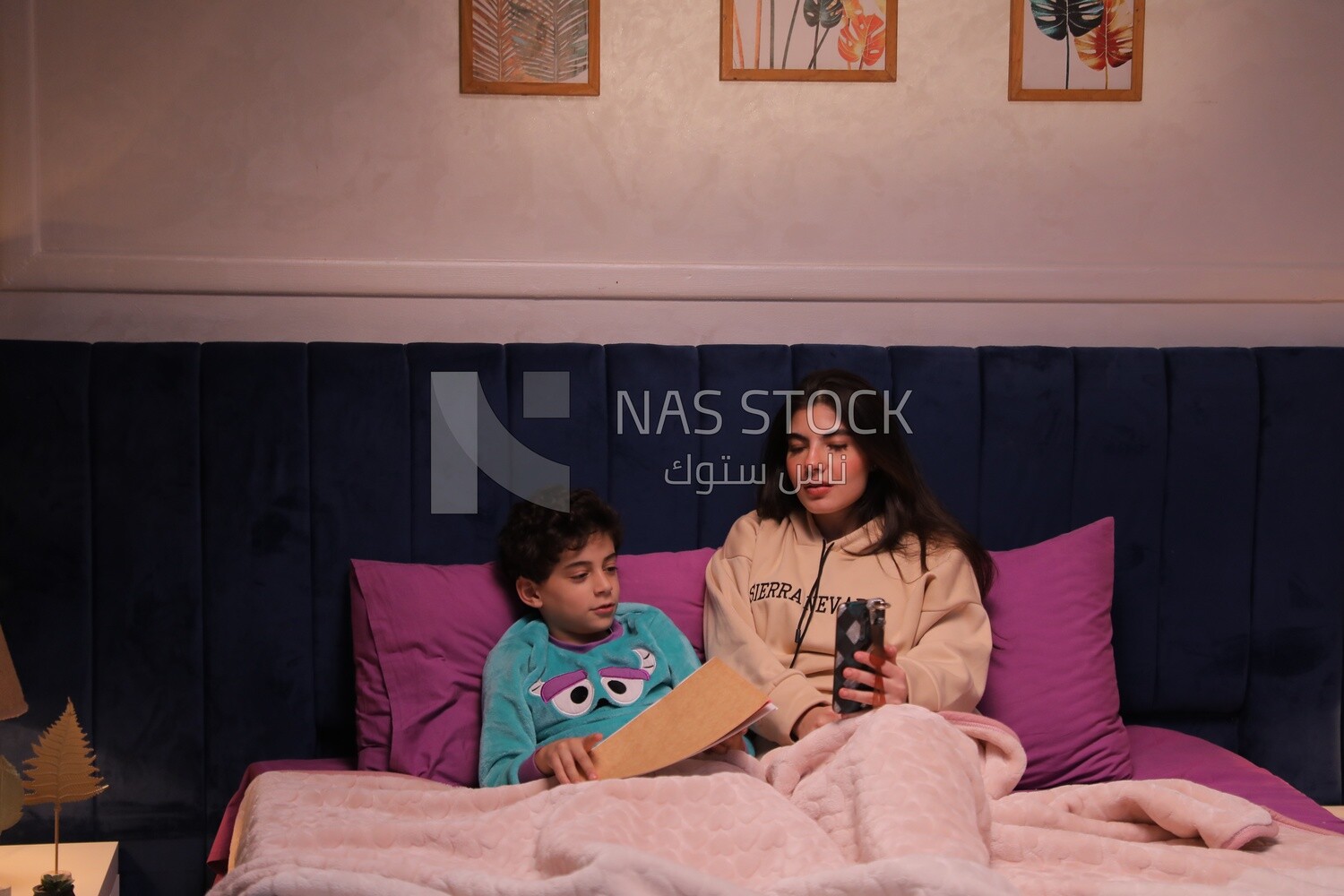 a woman reading a story to her son in bed