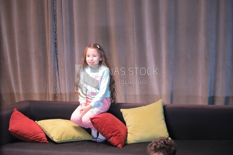 a girl sitting on the sofa in front of the television