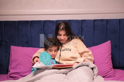 a woman reading a story to her son in bed