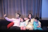 a family of four sitting on the sofa and taking a selfie