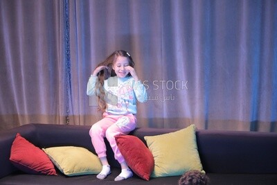 a girl sitting on the sofa in front of the television