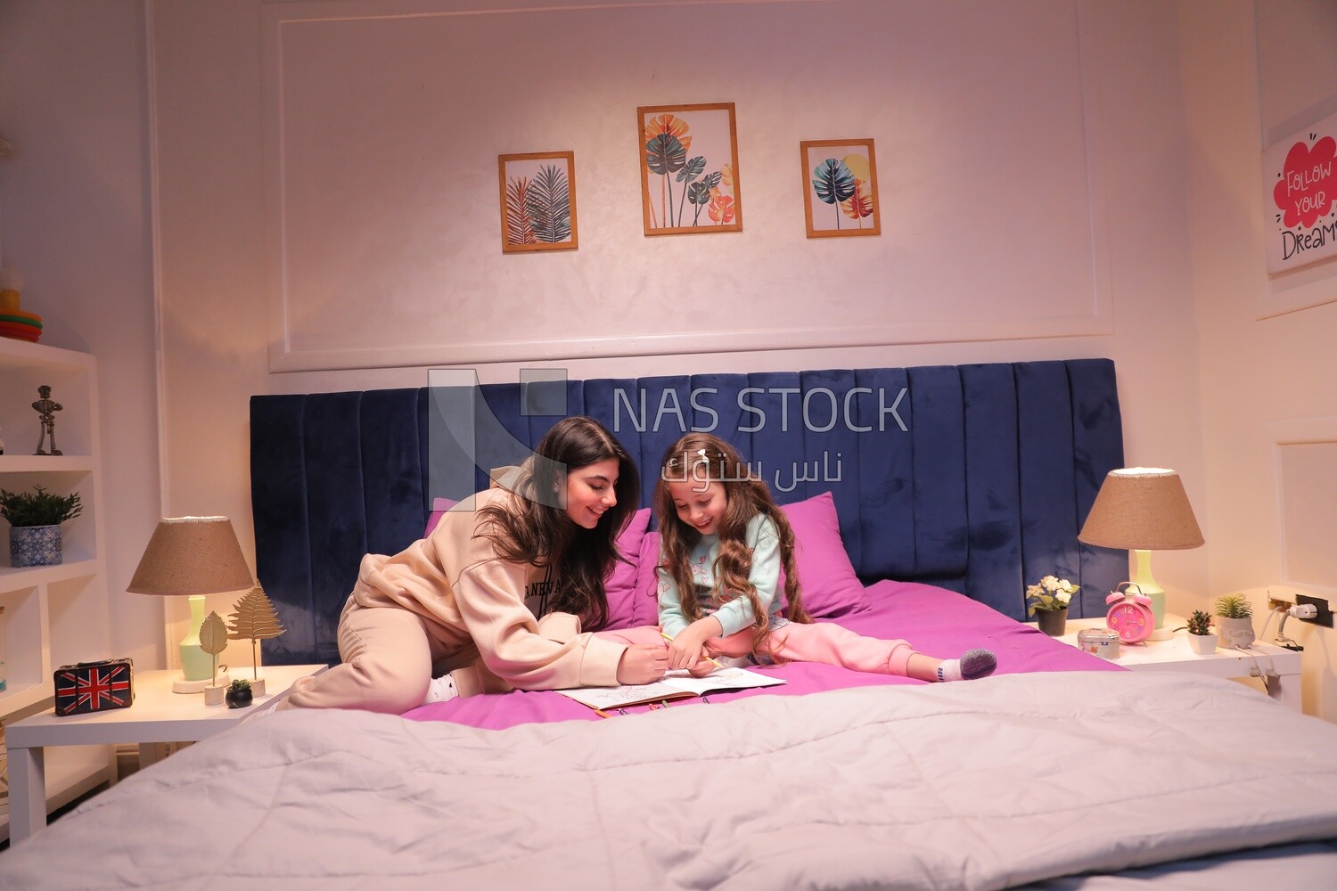 a mother with her daughter drawing together on the bed