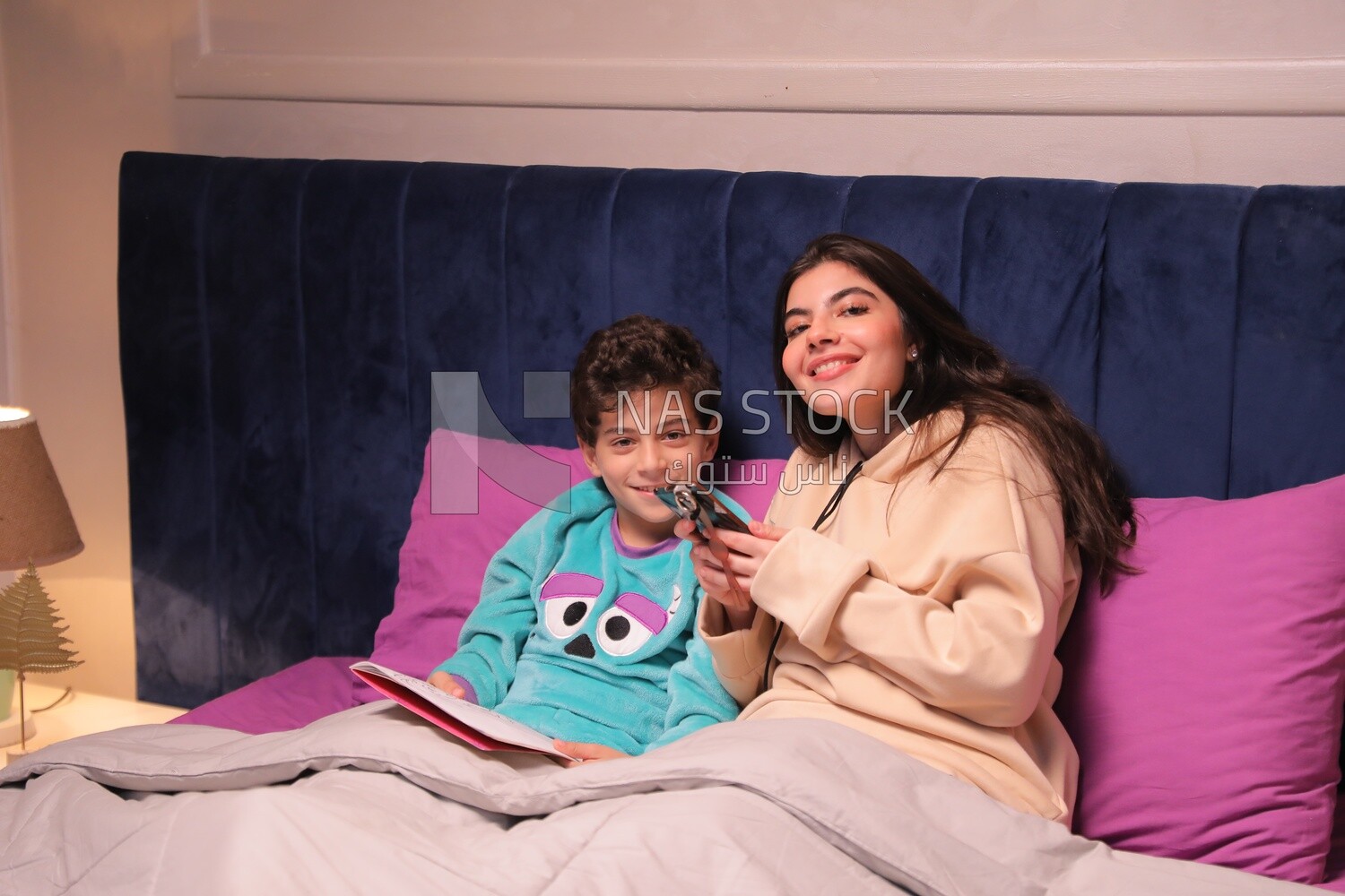 a woman reading a story to her son in bed