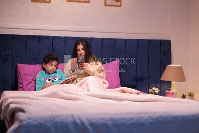 a mother sitting on the phone while her son studies