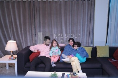 a family of four sitting on the sofa talking together
