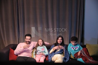 a family of four sitting on the sofa laughing and drinking a cup of tea