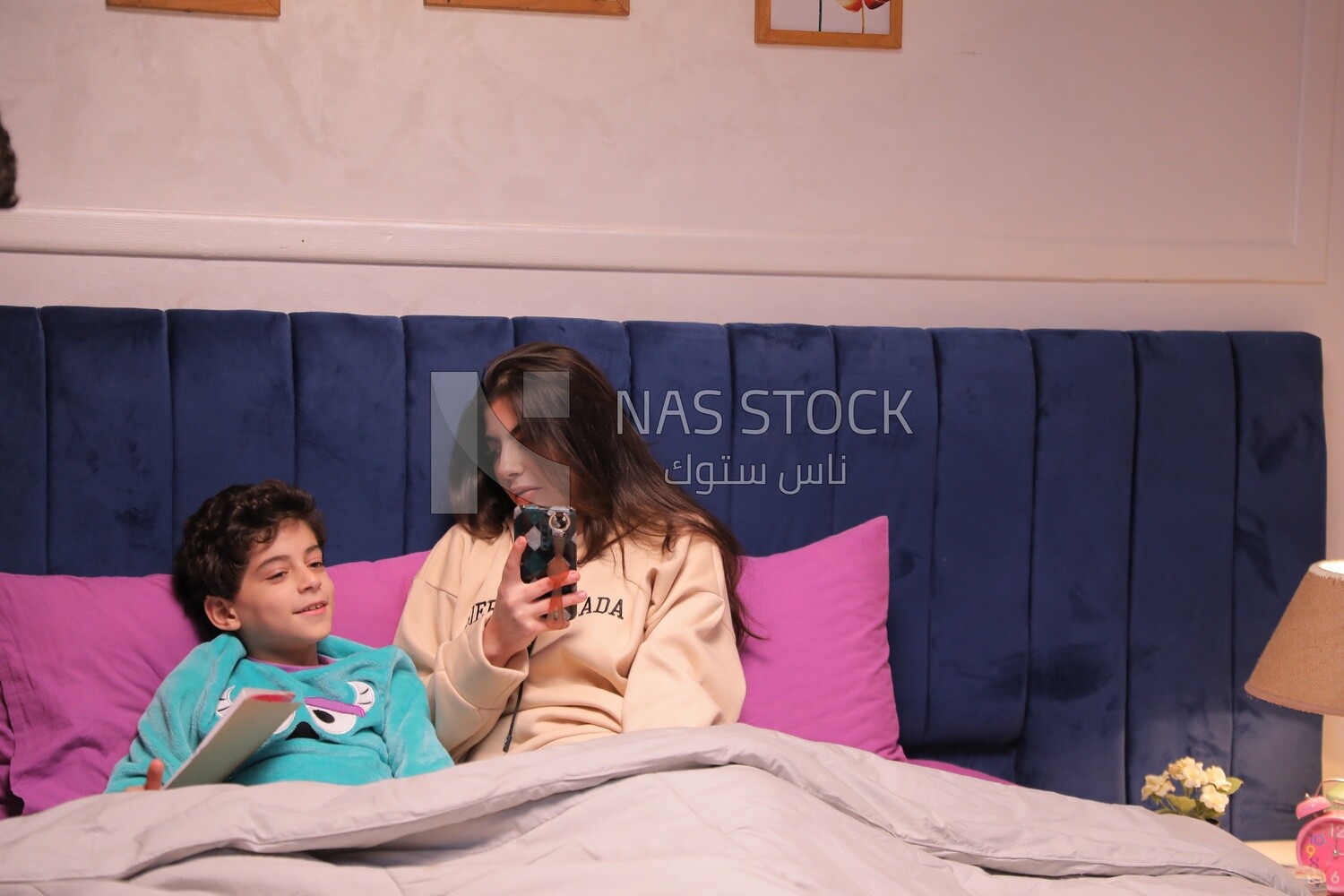 a mother sitting on the phone while her son studies