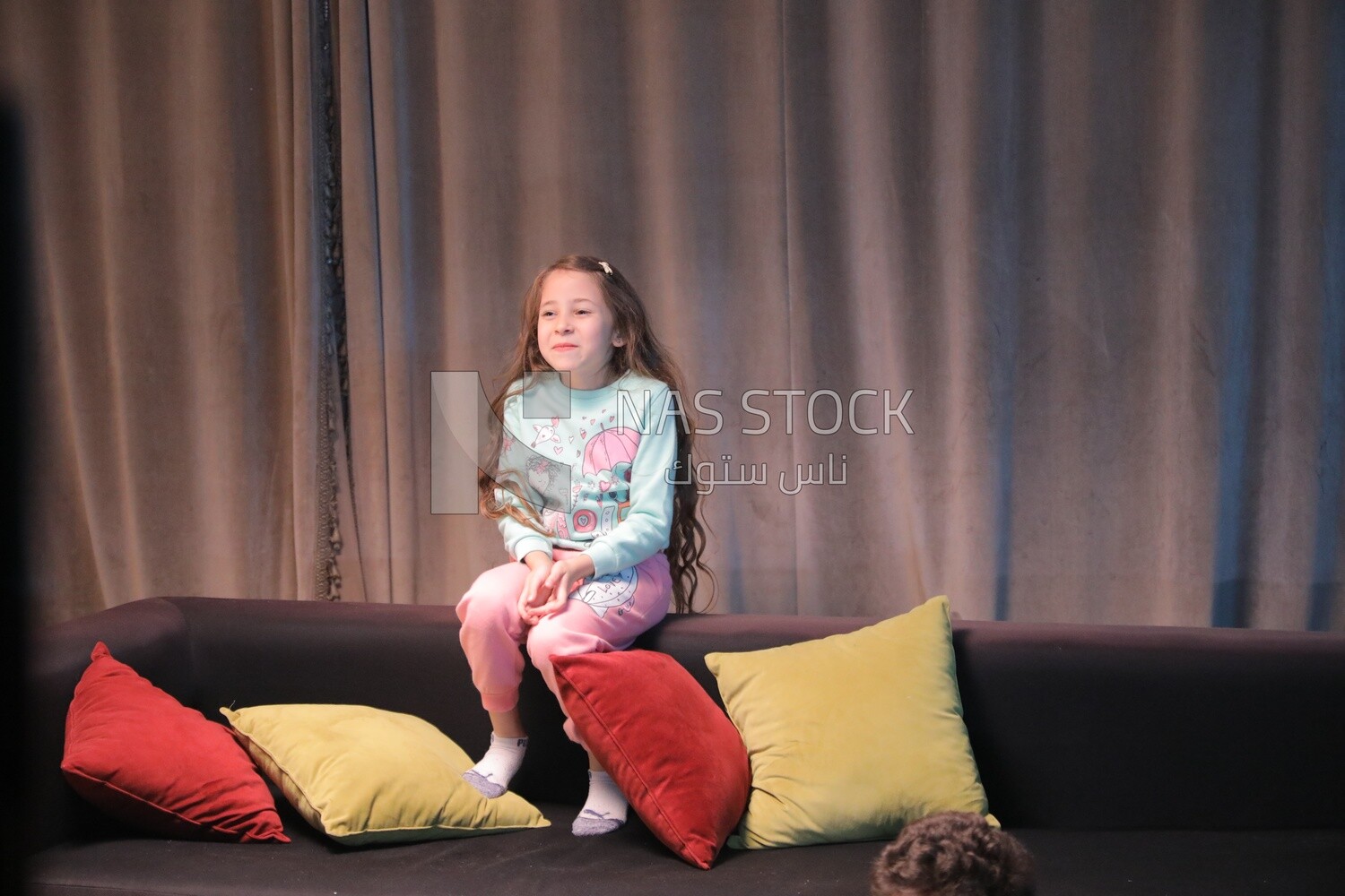 a girl sitting on the sofa in front of the television