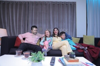 a family of four sitting on the sofa laughing