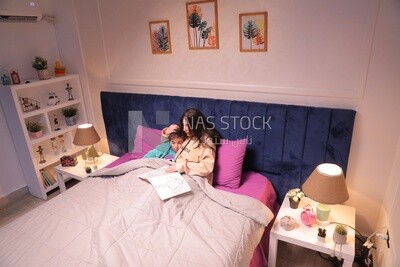 a woman reading a story to her son in bed