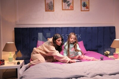 a mother with her daughter drawing together on the bed