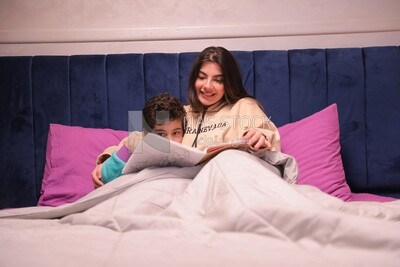 a woman reading a story to her son in bed