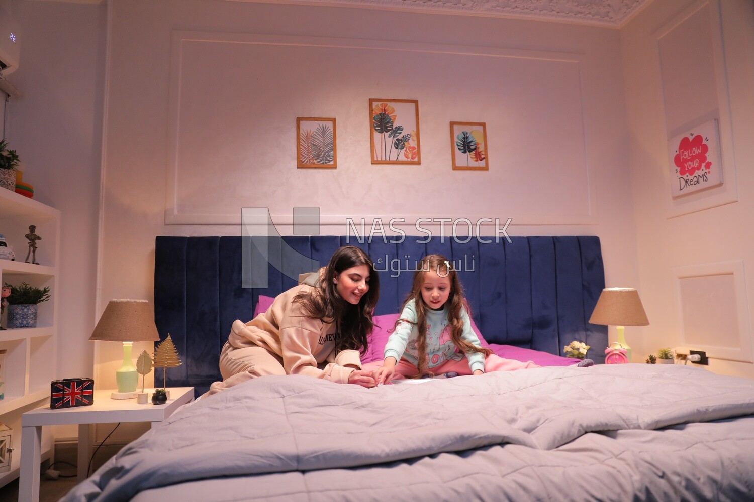 a mother with her daughter drawing together on the bed