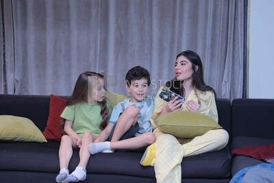 a mother with her kids sitting on the sofa and looking at the mobile