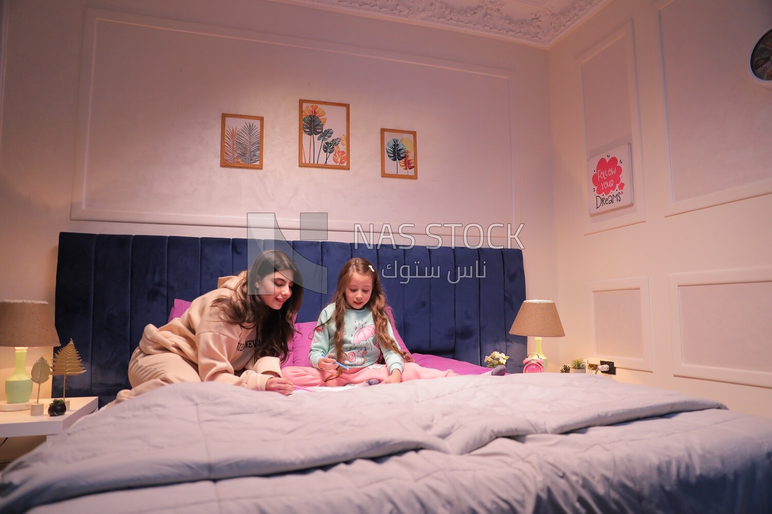 a mother with her daughter drawing together on the bed