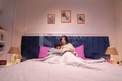 a woman reading a story to her son in bed