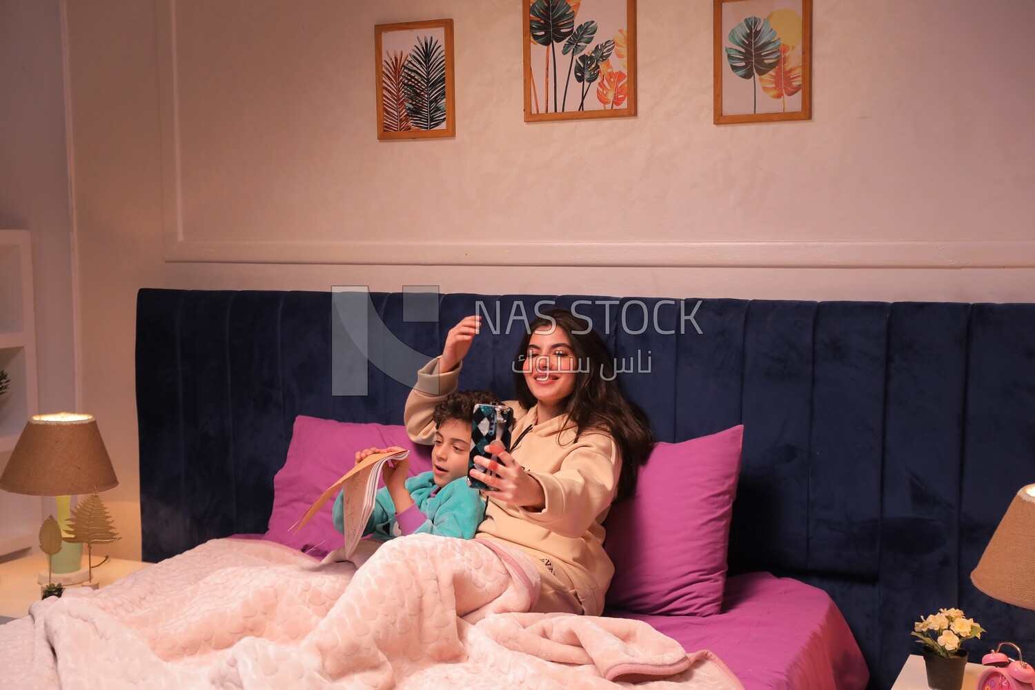 a woman reading a story to her child and taking a selfie in bed