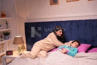 a mother sitting on the bed during his boy&#39;s sleep